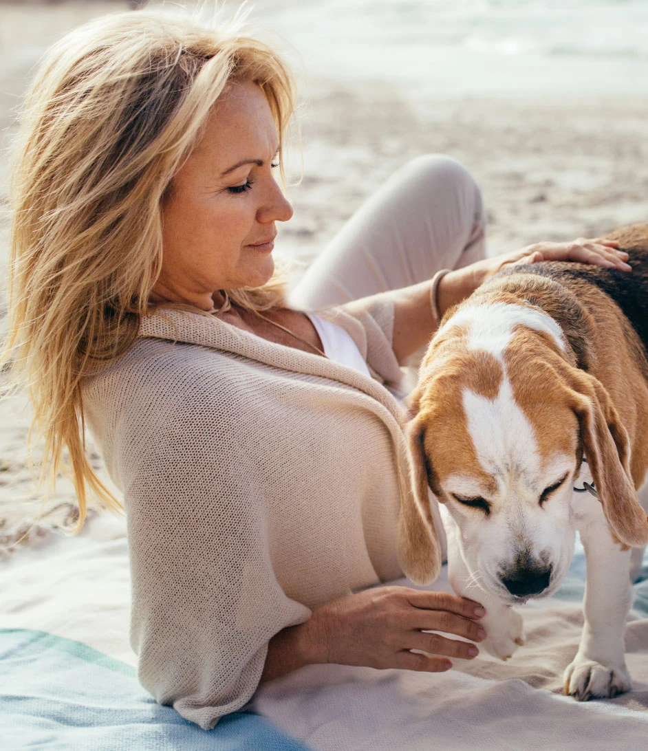 A woman sitting on the ground with her dog.