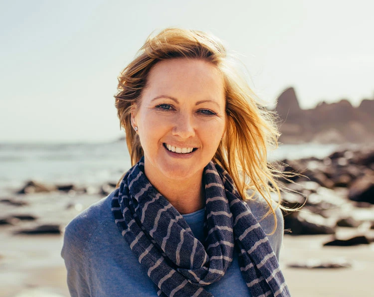 A woman wearing a scarf standing on the beach.